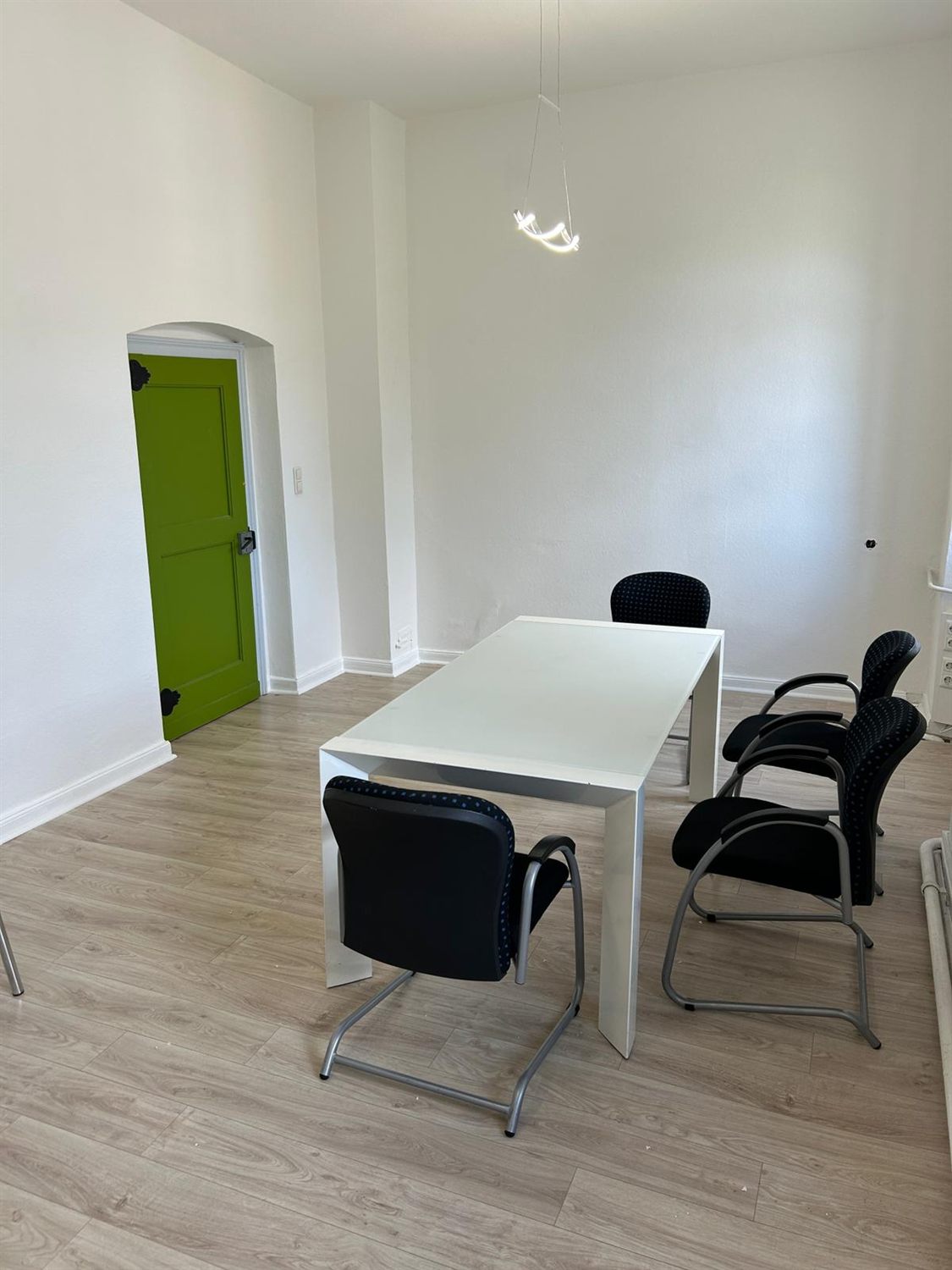 Renoviertes Büro mit Besprechungstisch und grüner Tür