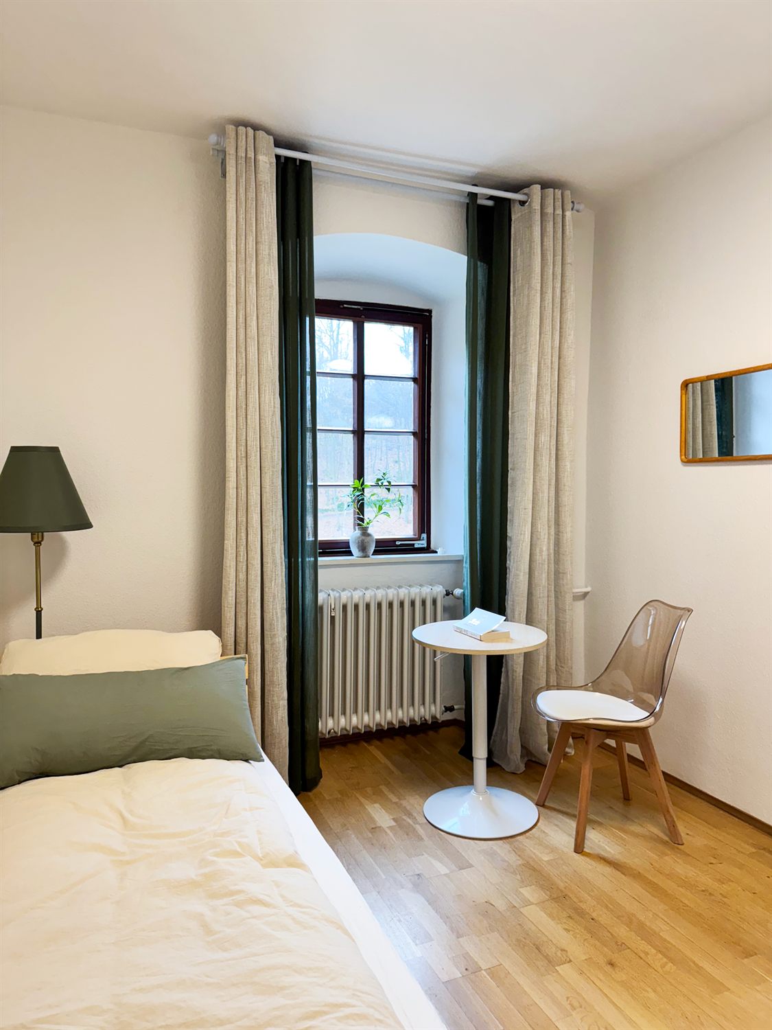 Einzelzimmer mit Bett, Tisch und Stuhl am Fenster