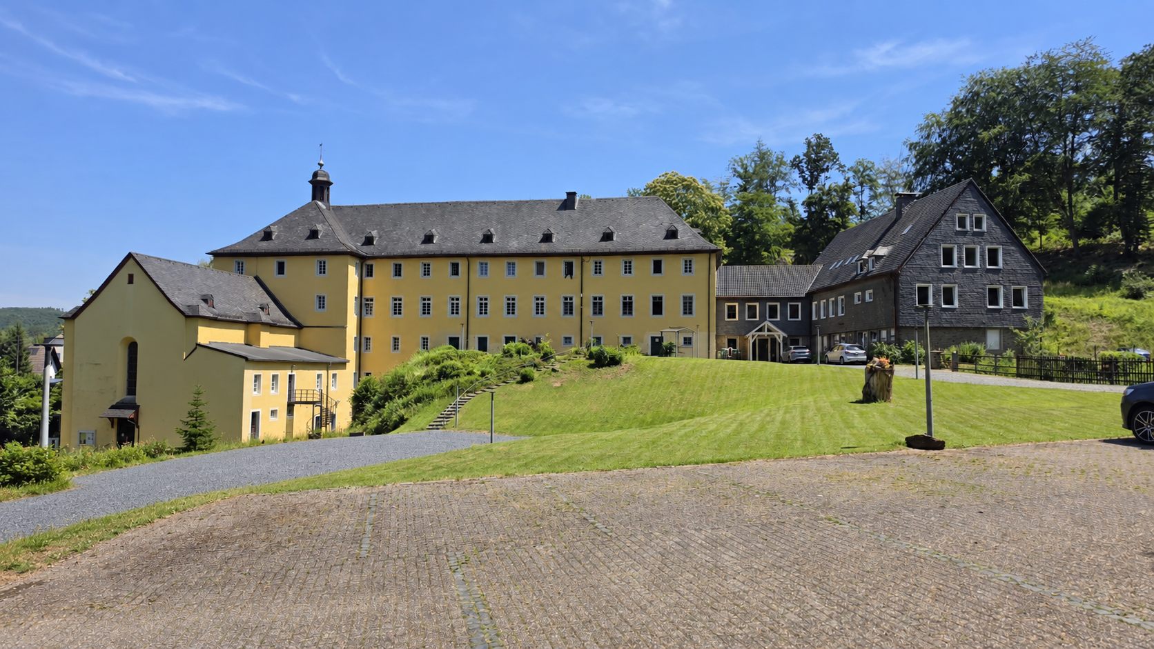 Kloster Marienthal: Kapelle, Hauptgebäude und Parkplatz bei blauem Himmel